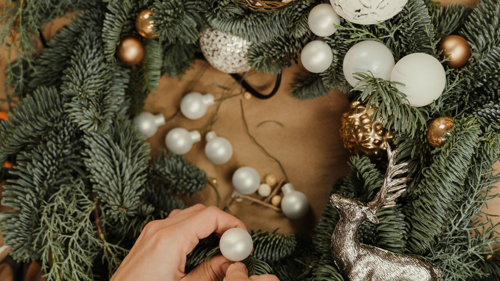 A neutral-toned wreath and a bundle of faux flowers styled together on a shelf for a minimalist decor look