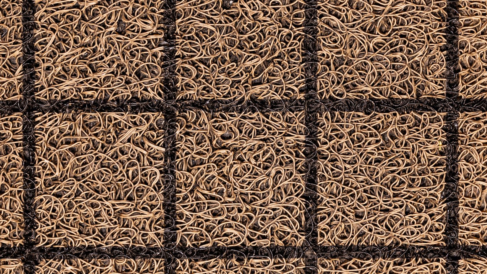 Textured coir doormat placed at a kitchen entrance on a tiled floor