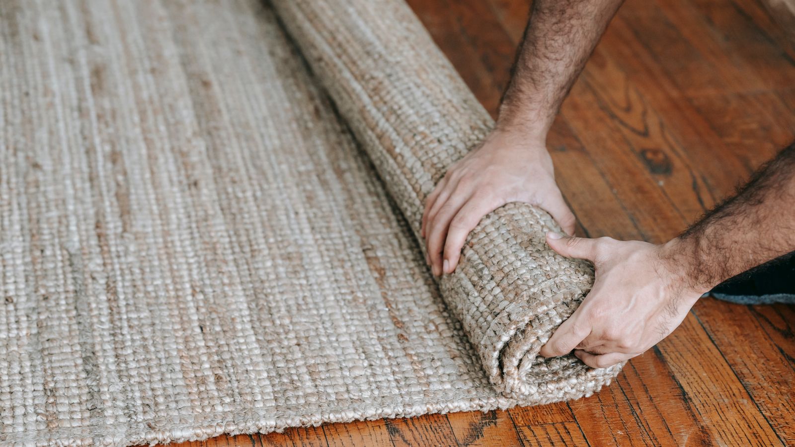 Rolled up woven area rug being prepared for placement in a kitchen