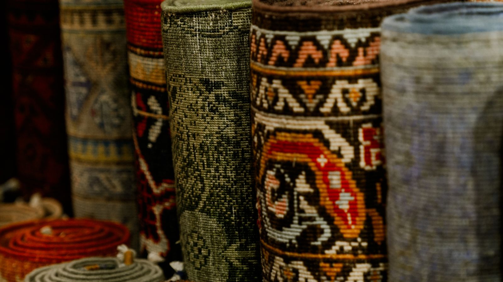 Neatly rolled rugs stacked on a shelf in a home storage closet