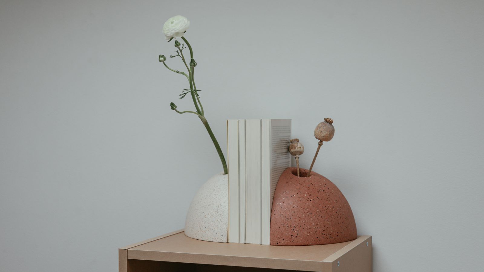 A pair of metal bookends holding upright books on a wooden shelf