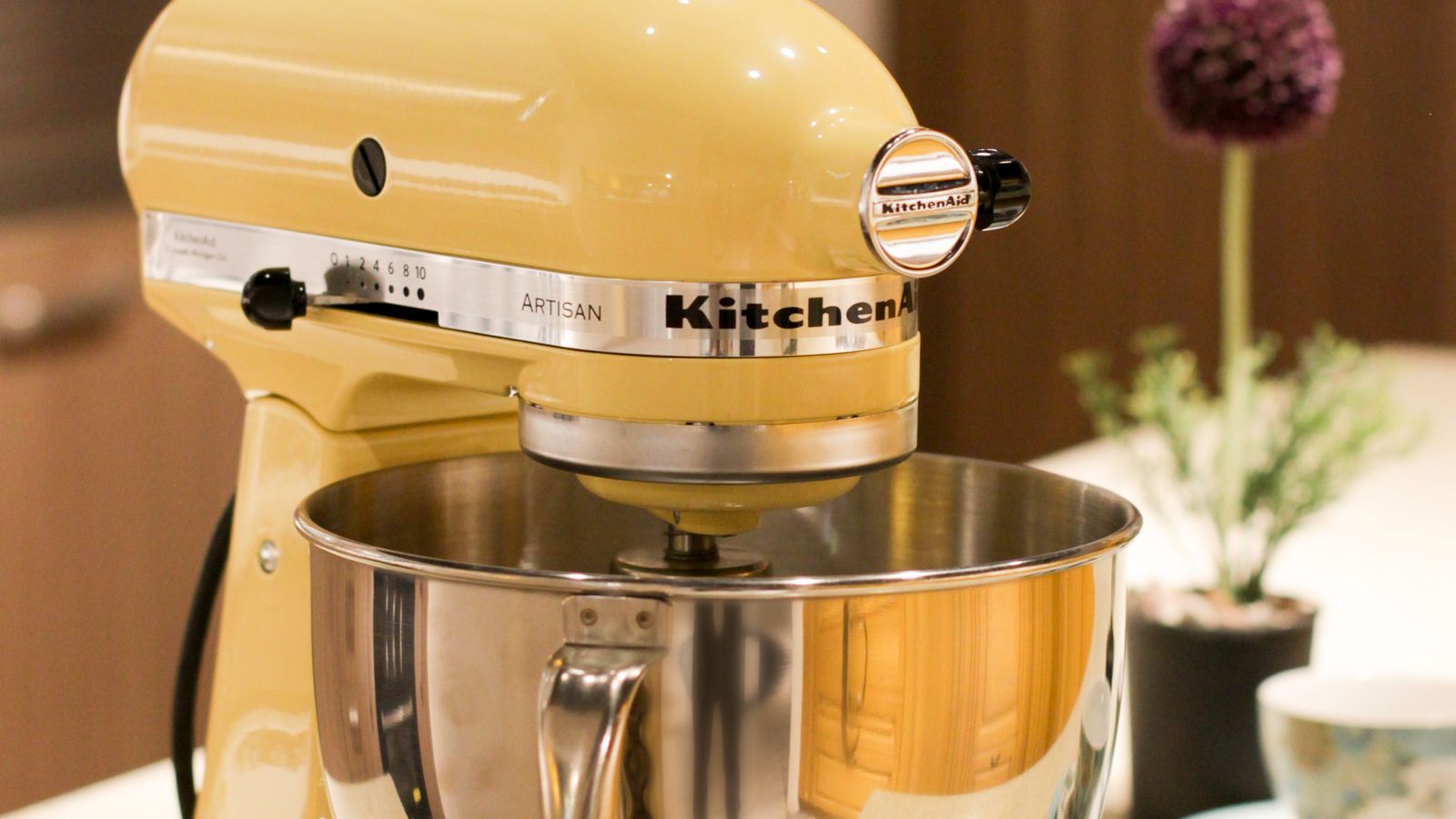 Close-up of a stand mixer bowl and attachments on a countertop near storage accessories