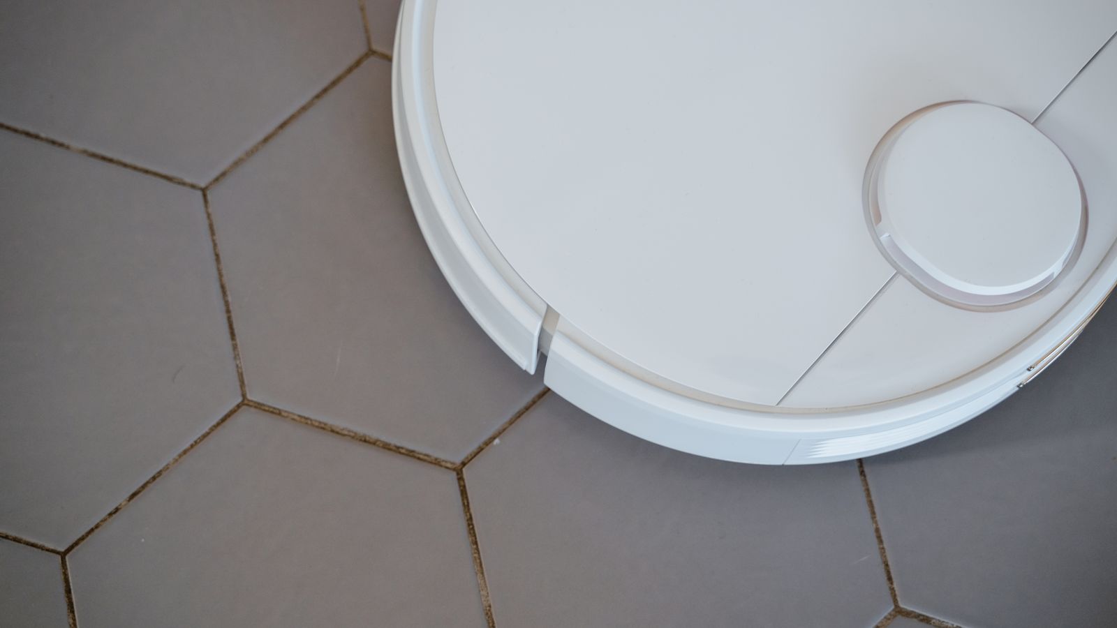 Close-up of a scrub brush cleaning dirty grout lines between floor tiles