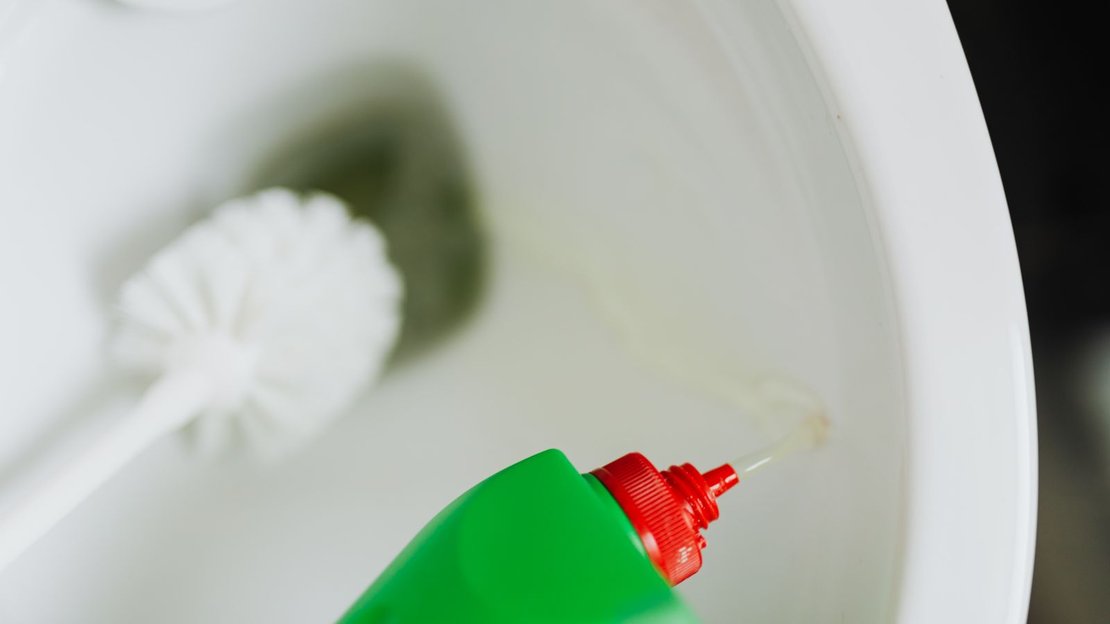 Bathroom cleaning supplies including spray bottle and brush next to a toilet bowl