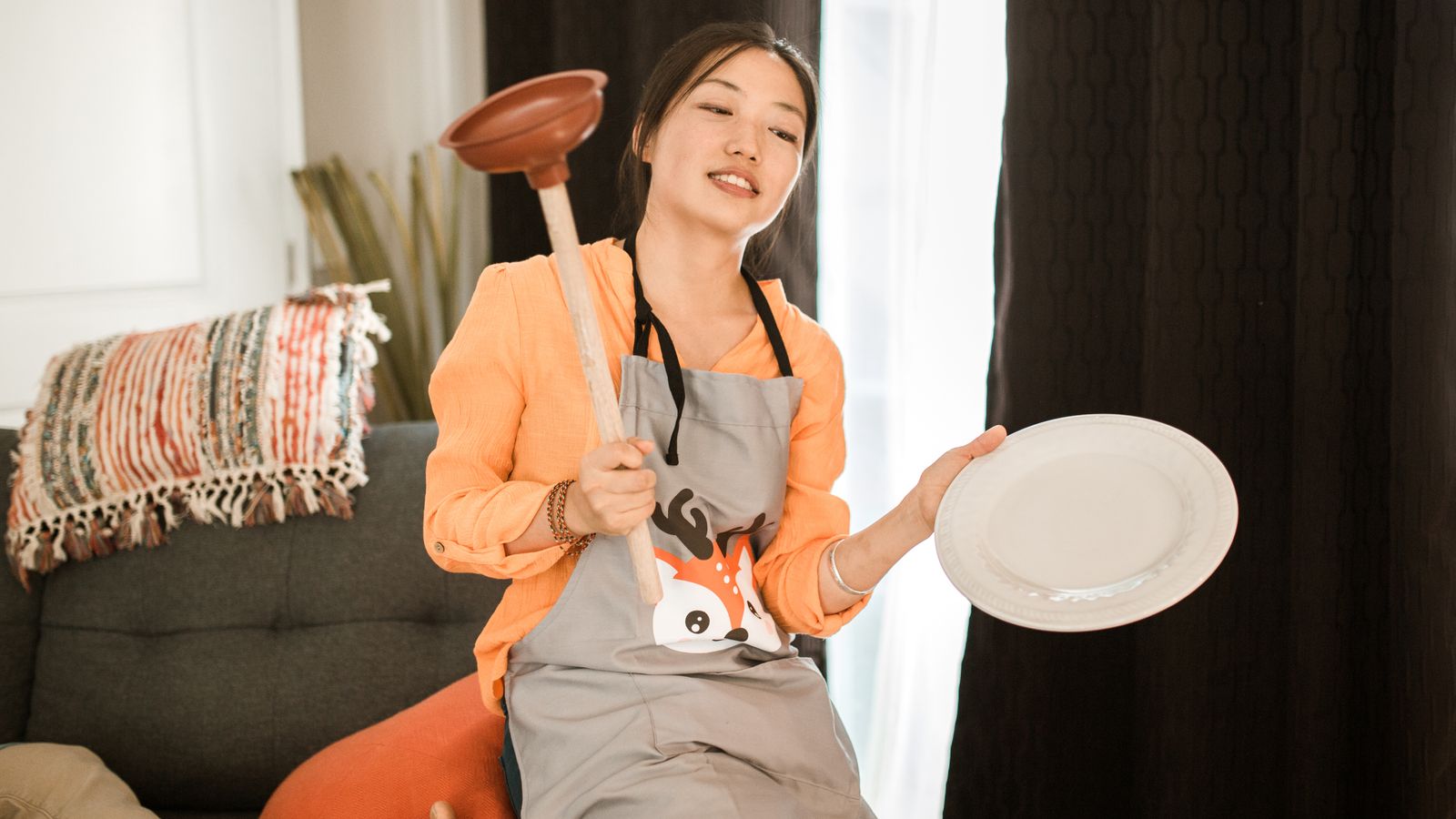 Person holding a flange-style toilet plunger in a bathroom setting