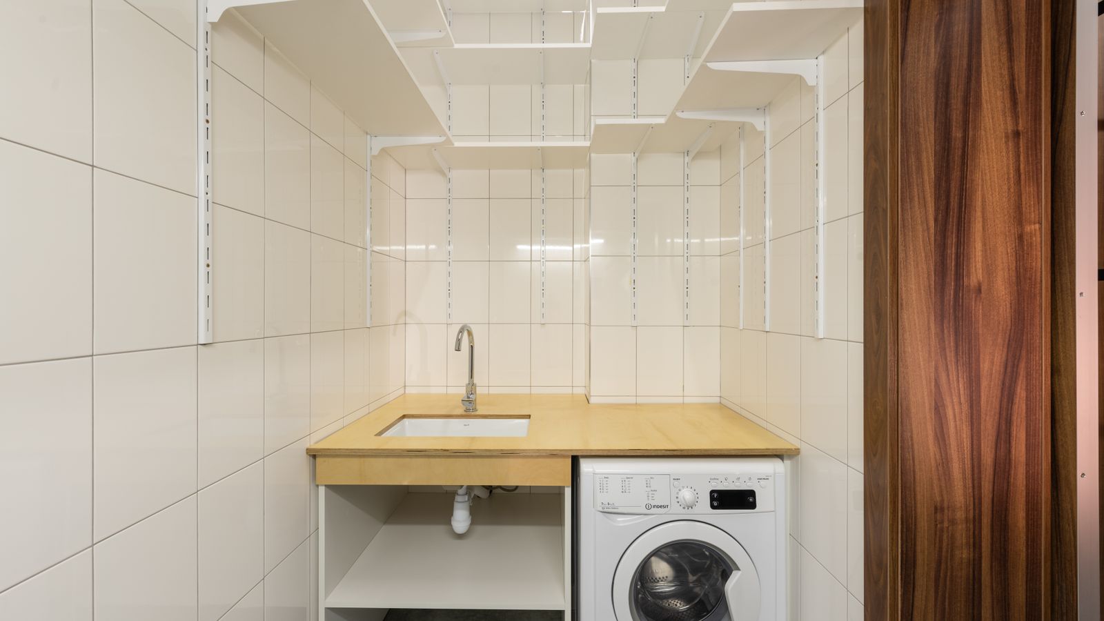 Wall-mounted wire shelving unit holding laundry detergent and folded linens