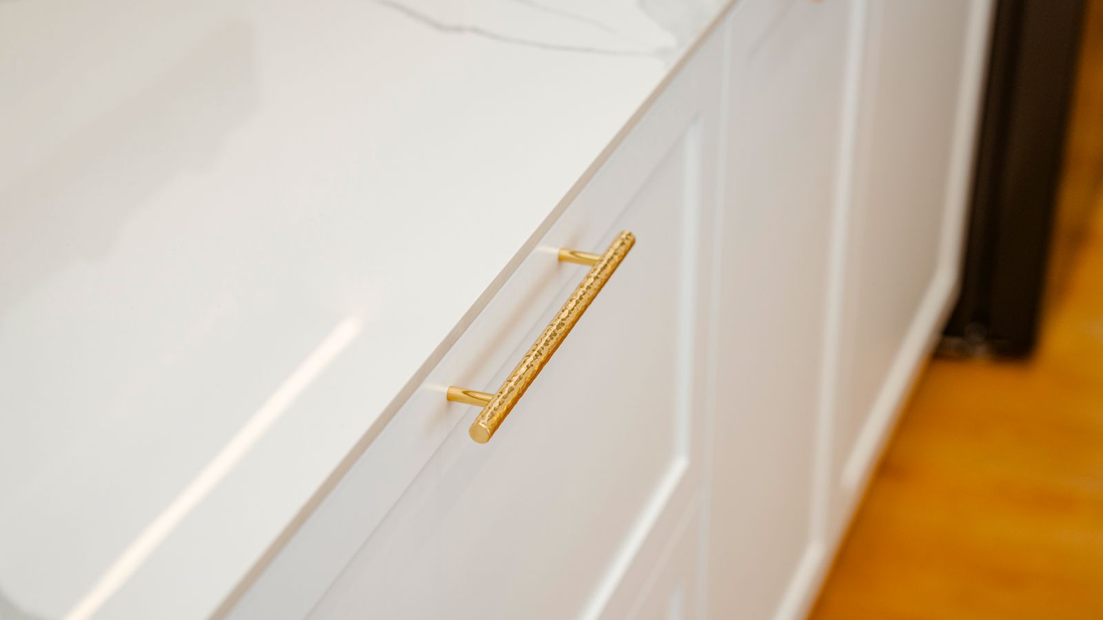 Elegant white kitchen cabinet drawer with gold pull hardware and marble countertop