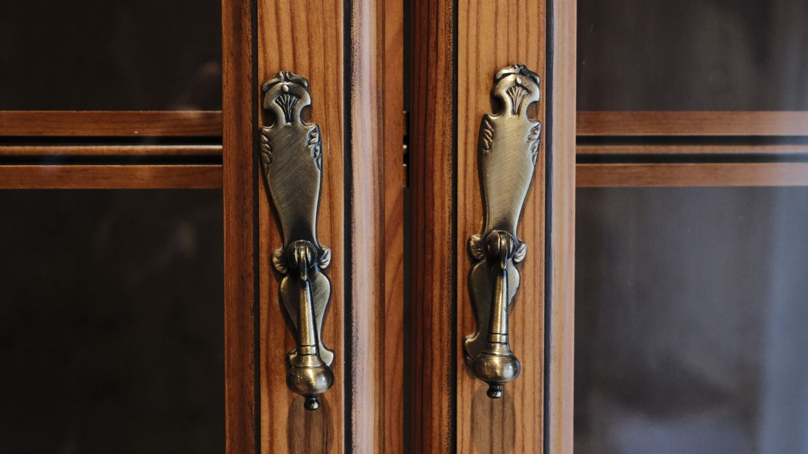 Close-up of brass cabinet hardware handles installed on wooden kitchen cabinet doors