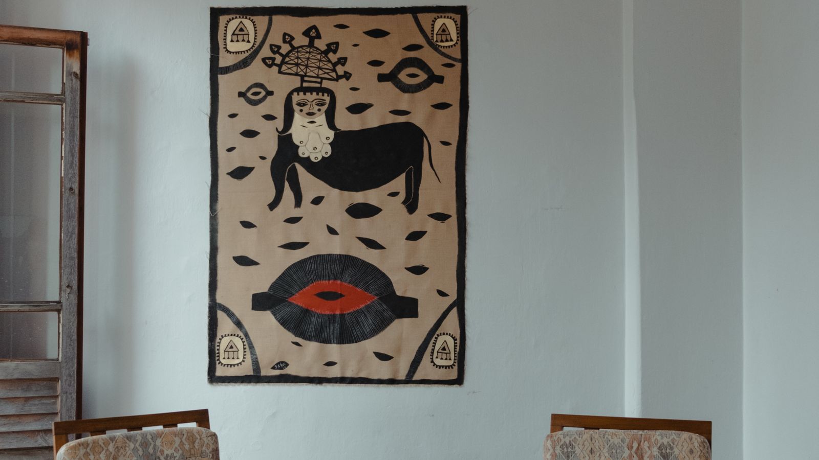 Woven tapestry hung as a large statement piece above a bohemian-style armchair