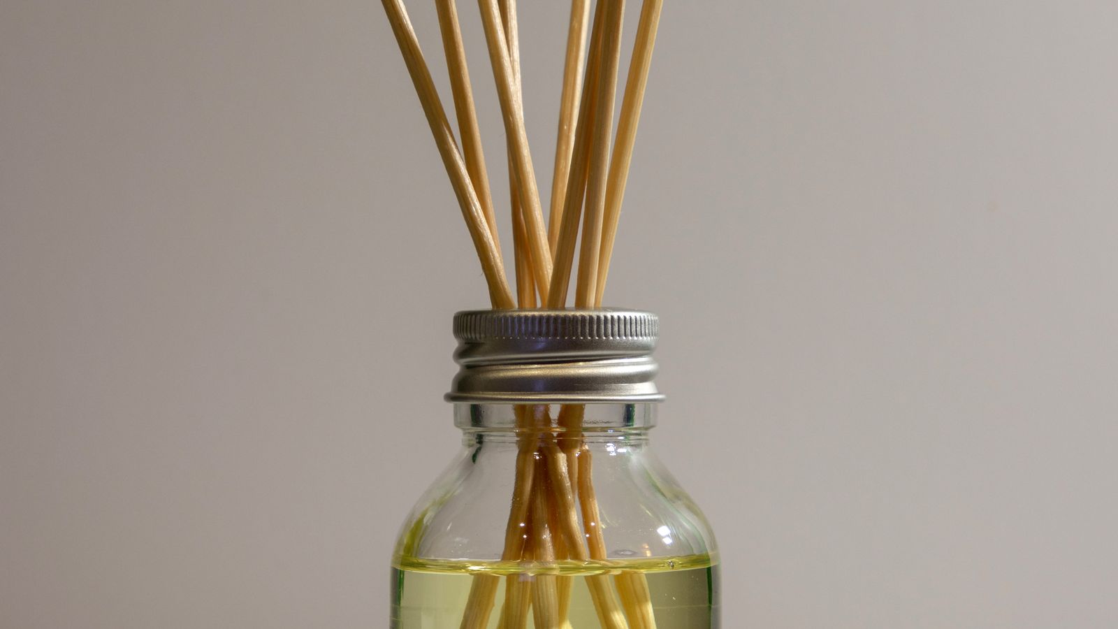 Elegant reed diffuser bottle on a countertop next to a granite surface in a clean kitchen